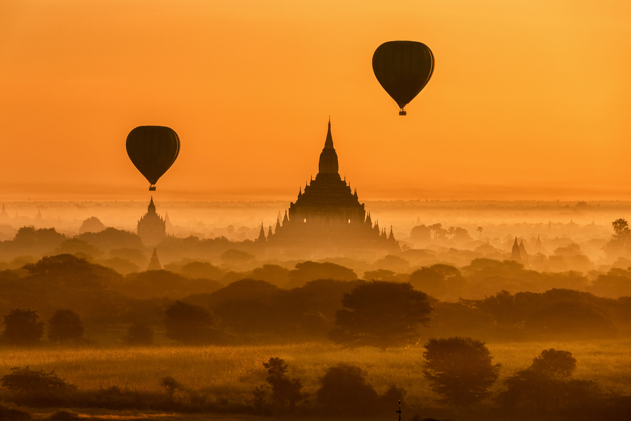 Hot-air balloons rising over the dawn sky at Bagan with a Pagoda in the background